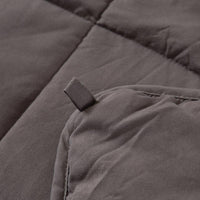 Person comfortably wrapped in grey weighted blanket, demonstrating its relaxing use.