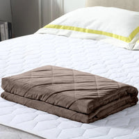 DreamZ weighted blanket folded on white bedding with soft natural light illuminating fabric texture.