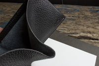 Close-up of black leather wallet corner highlighting detailed stitching.