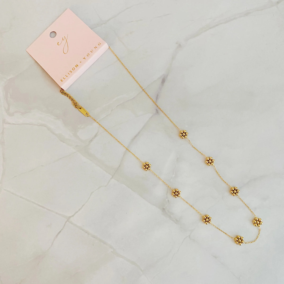 Golden bead flower necklace displayed on a flat surface, showing detailed flower beads.