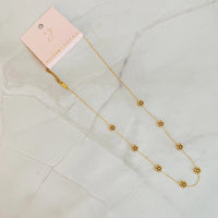 Golden bead flower necklace displayed on a flat surface, showing detailed flower beads.