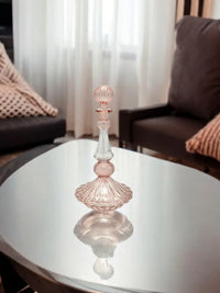 Intricate hand painted essential oil bottle made of hand blown clear glass with floral motifs.