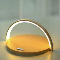 Sleek black wireless charger block holds a smartphone upright while charging on a white tabletop.
