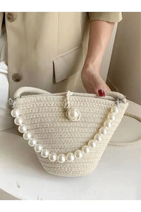 Top view of the bag emphasizing its simple clasp and pearl embellishments on the strap.