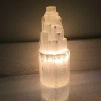 Close-up of selenite skyscraper lamp with light shining through translucent crystal