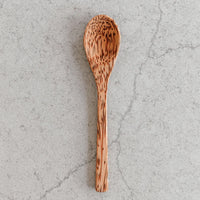 Wooden spoons displayed with a coconut bowl and ice cream, highlighting eco-friendly kitchenware.