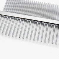 Close-up of red pet grooming comb showing dense and sparse stainless steel teeth and hollow handle design