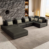 Large black modular sectional sofa with chaise lounge, upholstered in fabric, shown in a spacious living room.