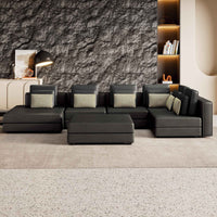 Large black modular sectional sofa with chaise lounge, upholstered in soft fabric, arranged in a spacious living room.