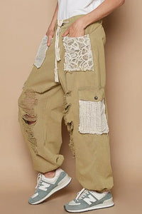 Front view of distressed washed jeans with crochet patches on a mannequin against a neutral background.