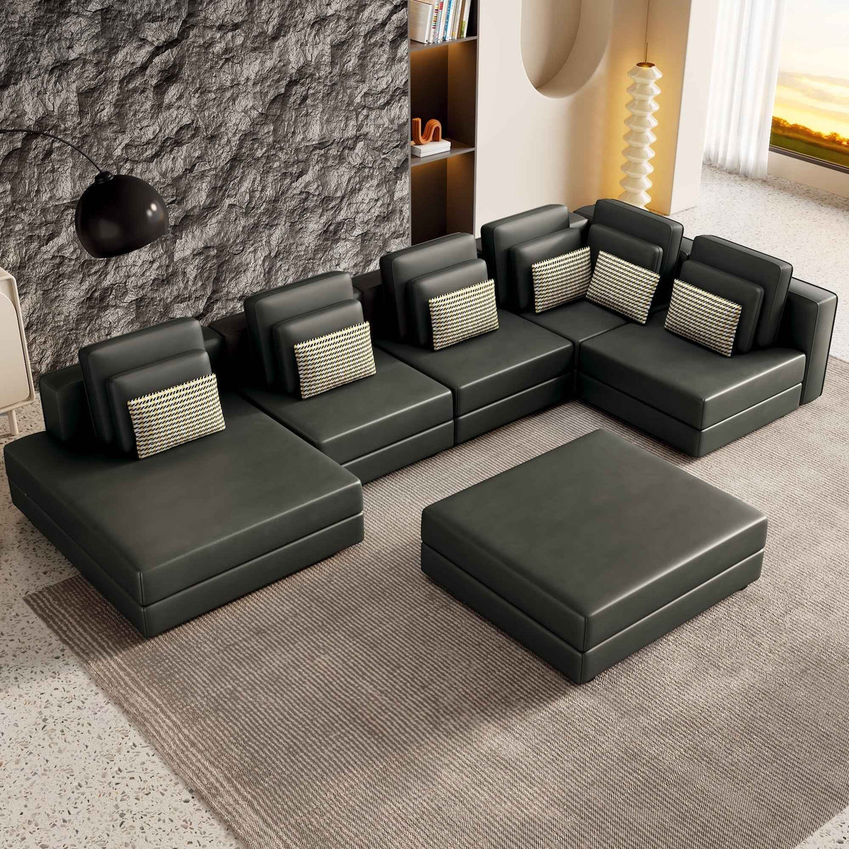 Large black modular sectional sofa with a chaise lounge, upholstered in soft fabric, set in a bright living room.