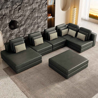 Large black modular sectional sofa with a chaise lounge, upholstered in soft fabric, set in a bright living room.