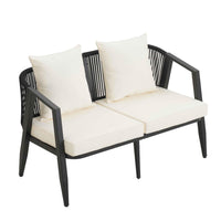 Set of four cushioned outdoor chairs and table with iron frames placed on a stone flooring outdoors.