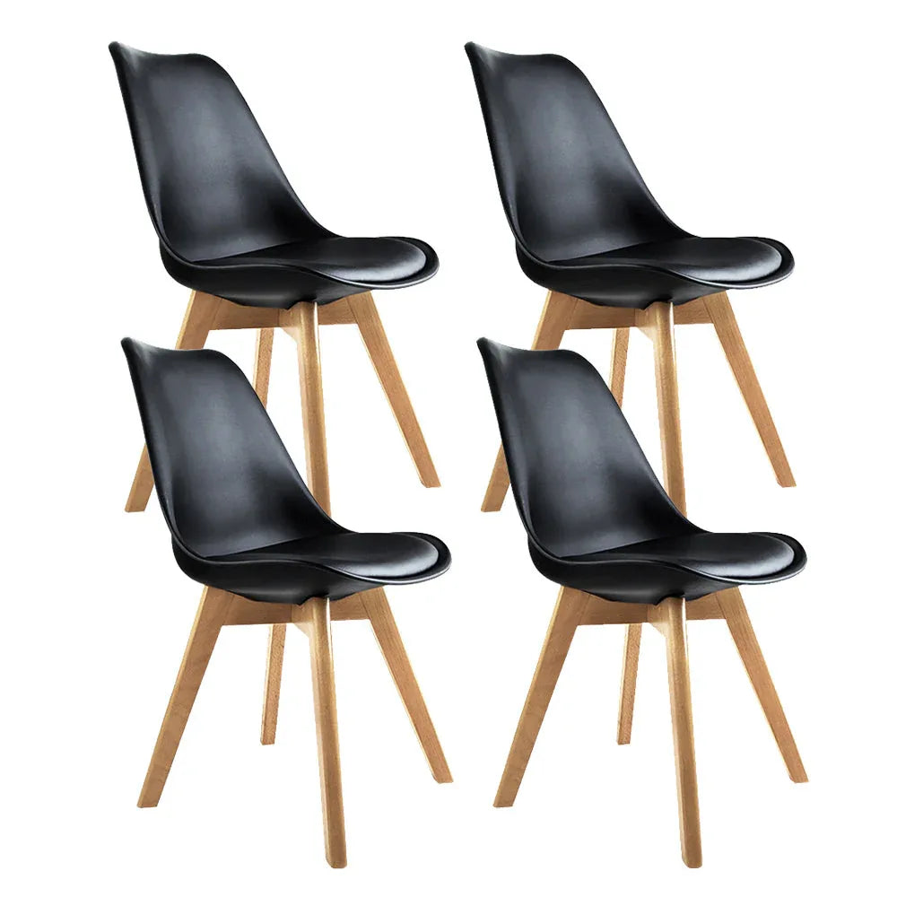 Set of four black padded dining chairs with wooden legs arranged around a white table.