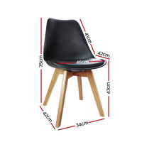 Close-up of a single black padded dining chair showing smooth PU leather and wooden legs.