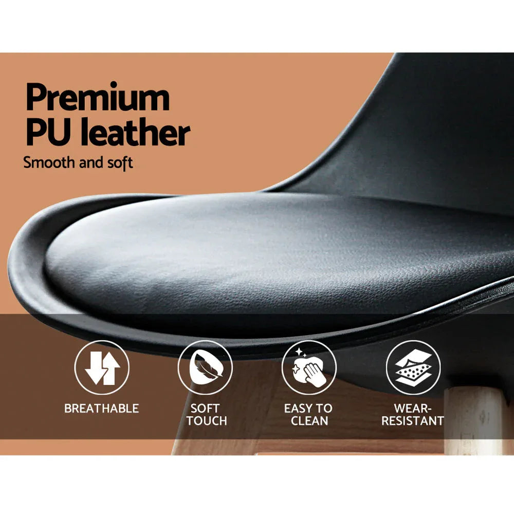 Detail of the chair’s cushioned black seat and sturdy wooden legs on a light background.