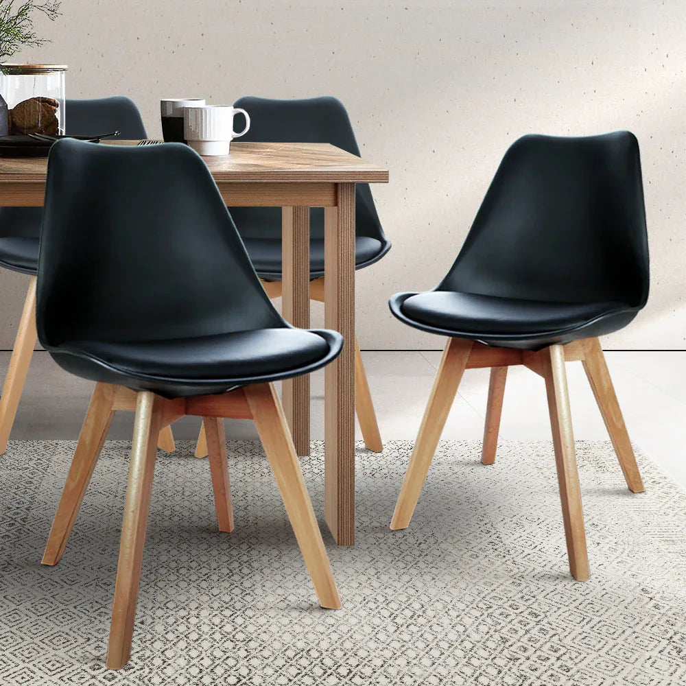 Set of four black leather dining chairs from an angled perspective showing their structure.