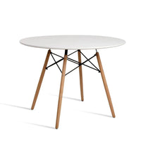Round white dining table with wooden Eiffel-style legs on a light floor
