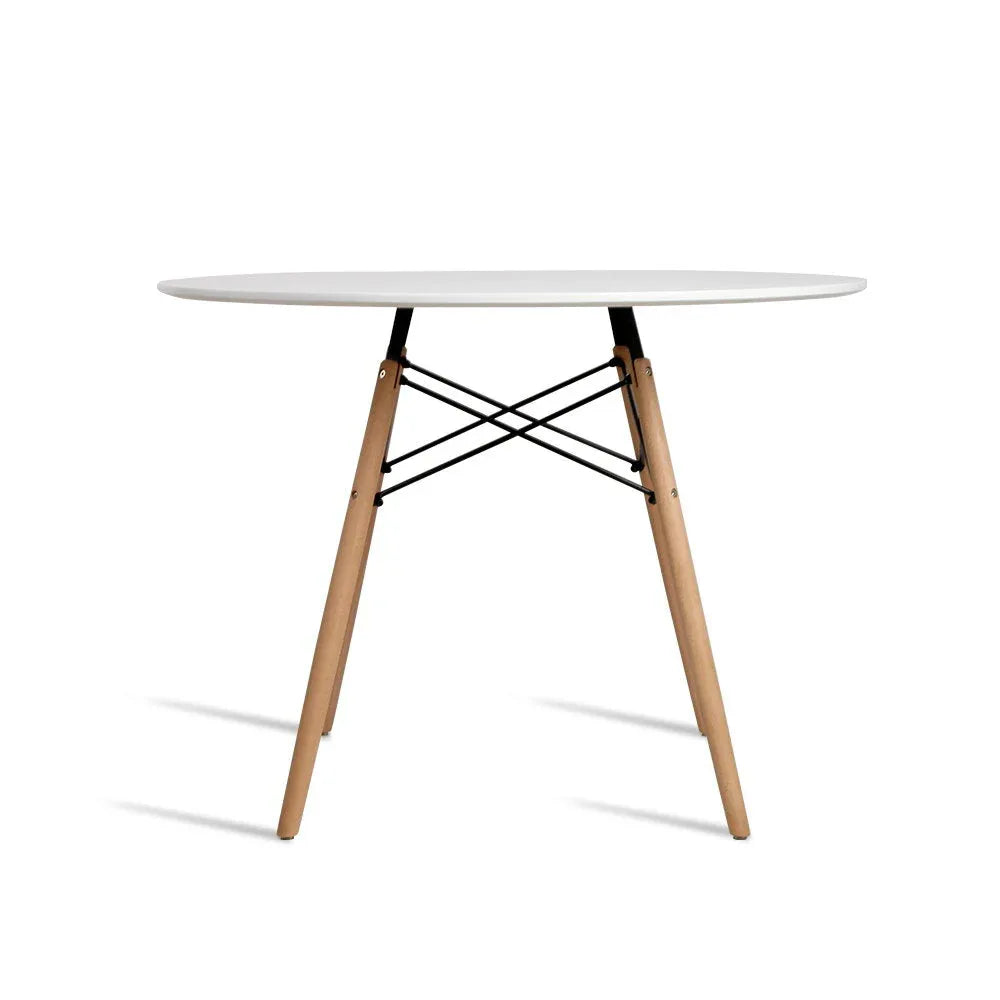 White round dining table with four wooden legs displayed in bright room