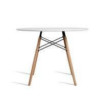 White round dining table with four wooden legs displayed in bright room