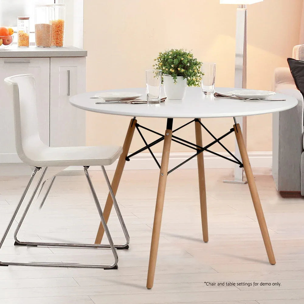 Assembled white round dining table with wooden legs shown in minimalistic room
