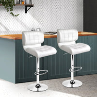 Bar stools with adjustable chrome bases, showing footrests and plush white seats.