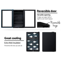 Devanti 115L bar fridge standing on kitchen countertop next to beverages and snacks.