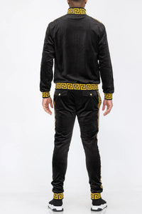 Black velour track pants with gold stripes hanging, showing elastic waistband and cuffs.