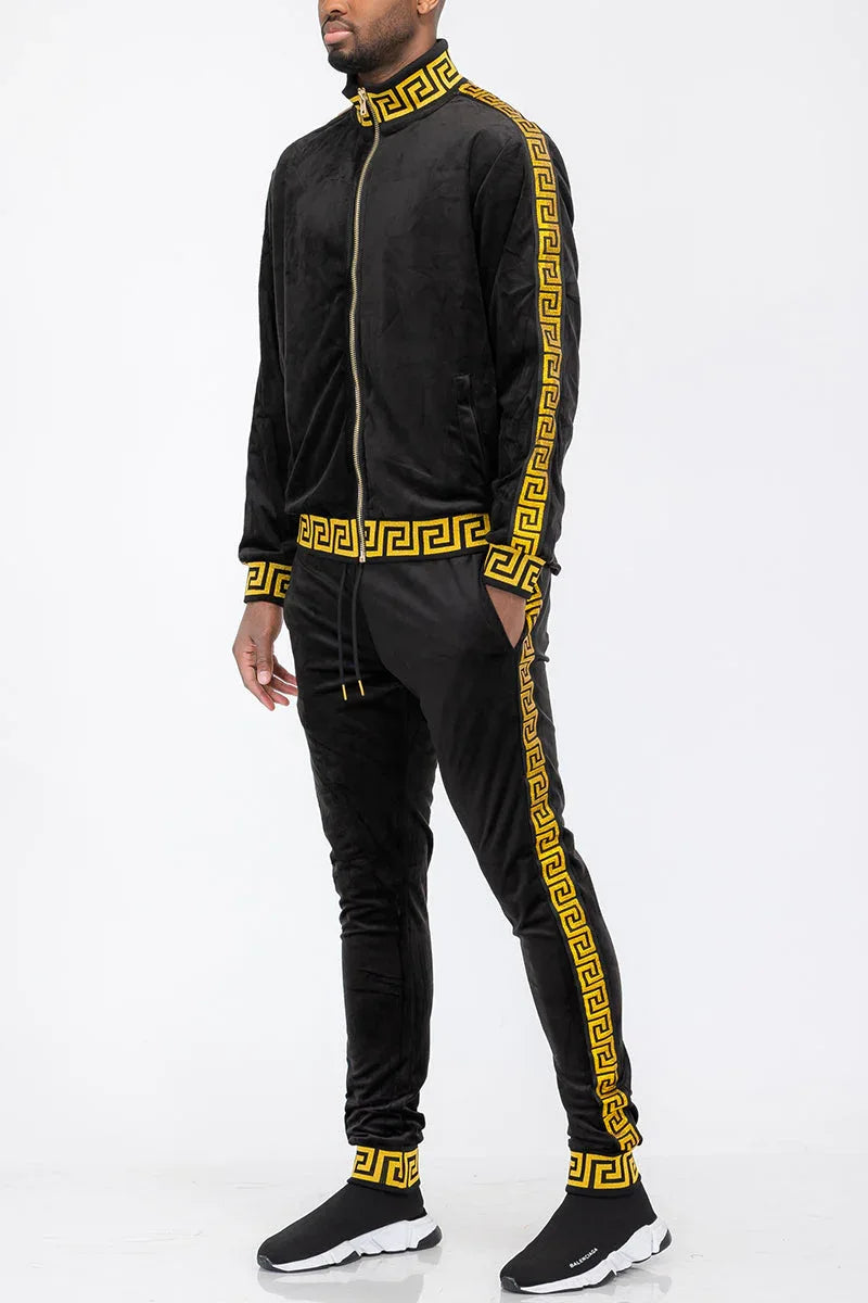 Black velour track jacket with gold accents displayed on a hanger against a white background.