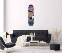 Close-up of Drake Skateboard hanging on living room wall above a console table with plants.