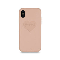 Close-up of compostable pastel pink phone case featuring a small engraved heart design.