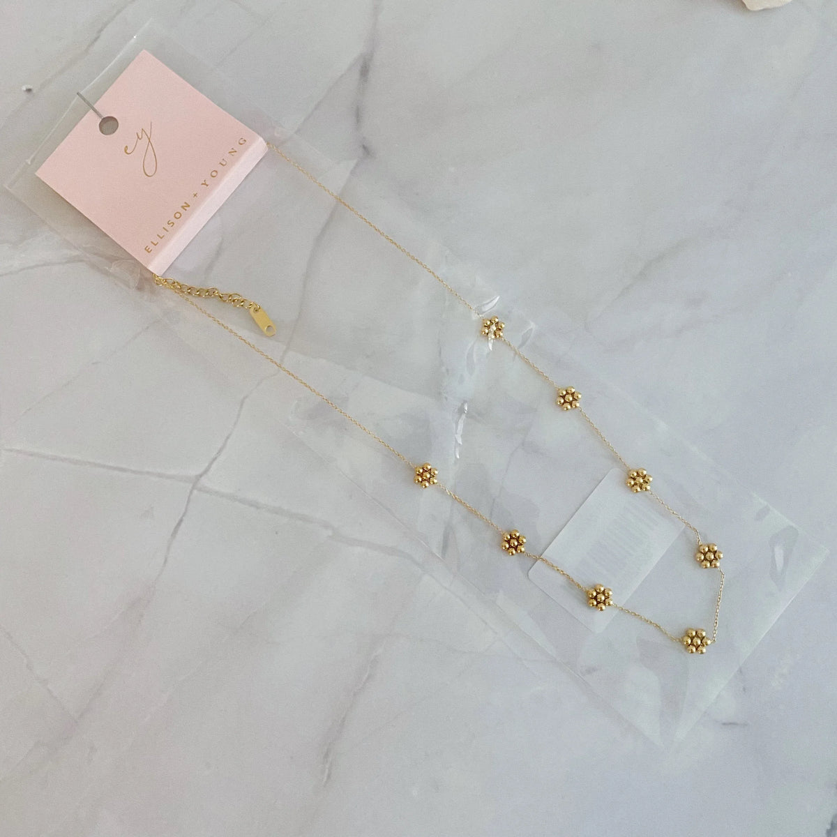 Close-up of necklace clasp and extender chain in gold finish on white background.