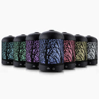Black Devanti aroma diffuser with enchanted forest pattern on top, placed on wooden surface.