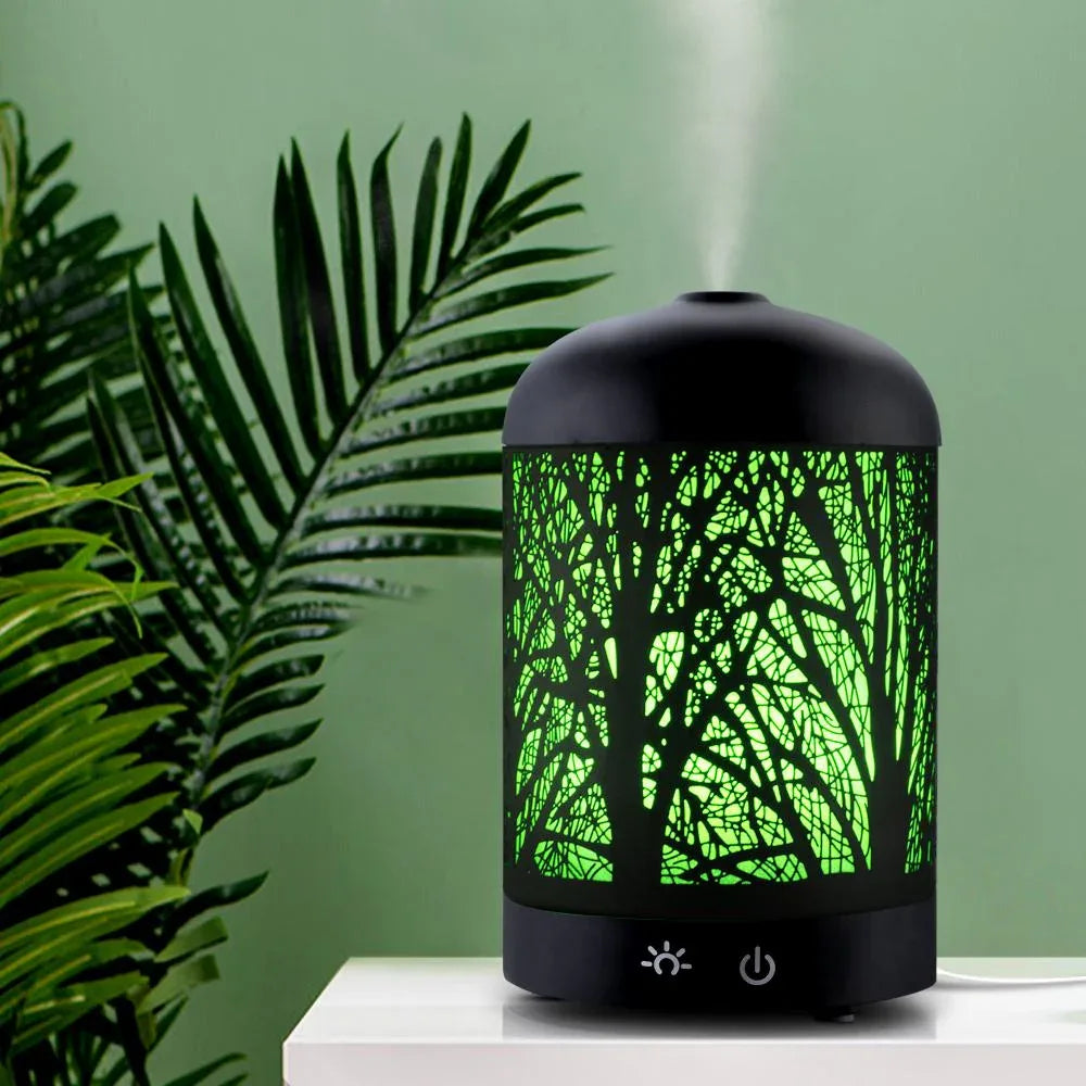 Black aroma diffuser on a table surrounded by various home accessories.
