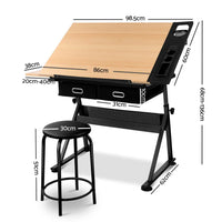 Close-up of natural wood desktop of drafting table with black metal frame and side pigment shelf.