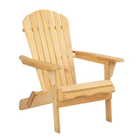 Wooden Adirondack beach chair displayed outdoors on sand with picnic basket and throw pillow.