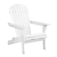 White foldable Adirondack chair placed outdoors on wooden deck with ocean in background.