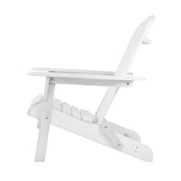 White Adirondack chair on patio near outdoor table under natural sunlight.