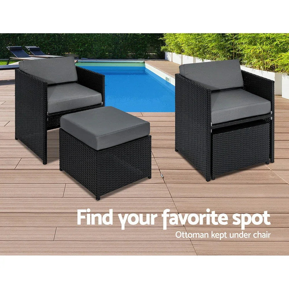 Wicker dining table set displayed by a garden wall with potted plants and decorative lights.
