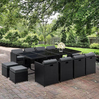 Full view of 13-piece wicker dining set on patio with ample seating and beige cushions.