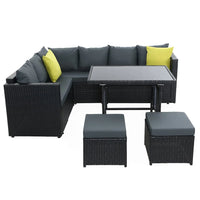 Corner arrangement of black outdoor wicker patio seats with beige cushions near a wall.