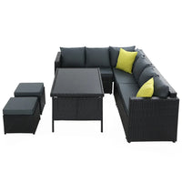 Black wicker patio dining set arranged with double seats and ottoman under bright outdoor light.