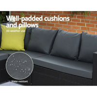 Modern black outdoor dining sofa set on stone floor with cream cushions and ottoman.