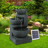 Blue bird bath fountain placed outdoors with solar panel nearby on grass