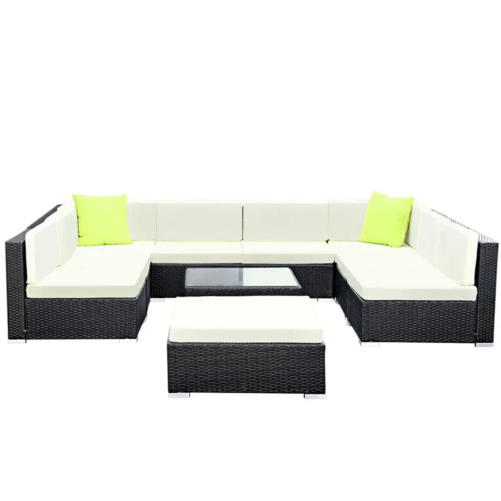 Corner view of outdoor wicker sofa set arranged on wooden deck with cushions.