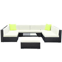 Corner view of outdoor wicker sofa set arranged on wooden deck with cushions.