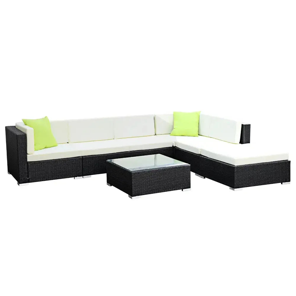 Side view of outdoor wicker sofa set in garden setting with lush green background.