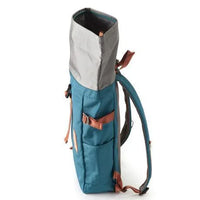 Side view of blue rolltop backpack highlighting size and arm holding shoulder strap.