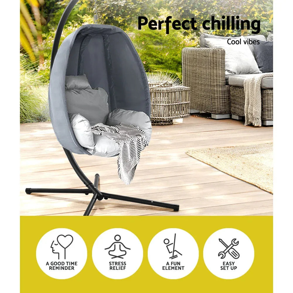 Rotating hanging egg chair with plush cushion on outdoor patio.