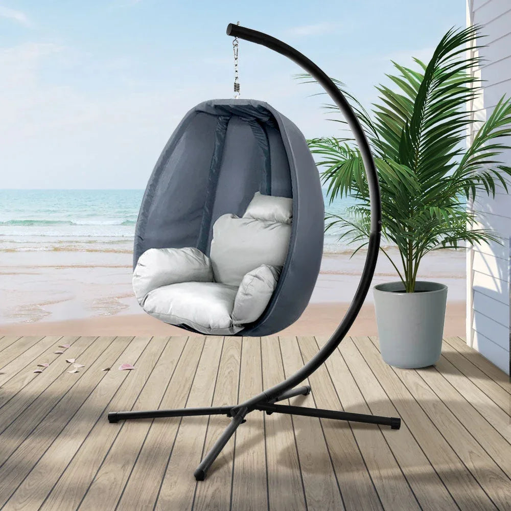 Relaxing outdoor egg hammock chair pod with soft cushion in neutral color.